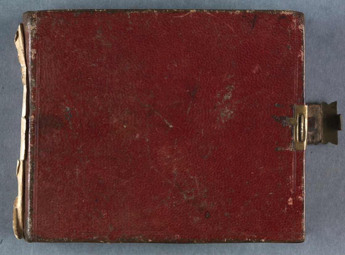 Photographie d’un livre à la couverture en cuir rouge, orné d’une serrure dorée et légèrement abîmé à l’arrière.