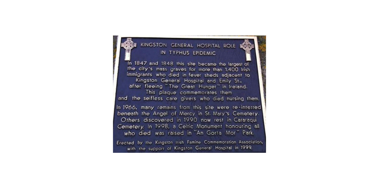 Photograph of plaque with gold inscription on dark background and flanked by Celtic Crosses on its upper right and left surface.