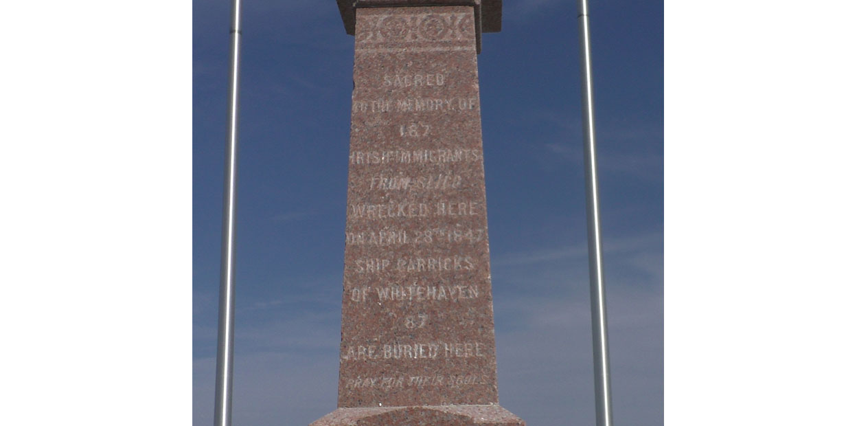 Grey monument with a bell installed in it. Below the bell is inscribed: Bell of the Carricks Irish Sailboat Shipwrecked at Cap-des-Rosiers on April 28, 1847. Found at Blanc Sablon.